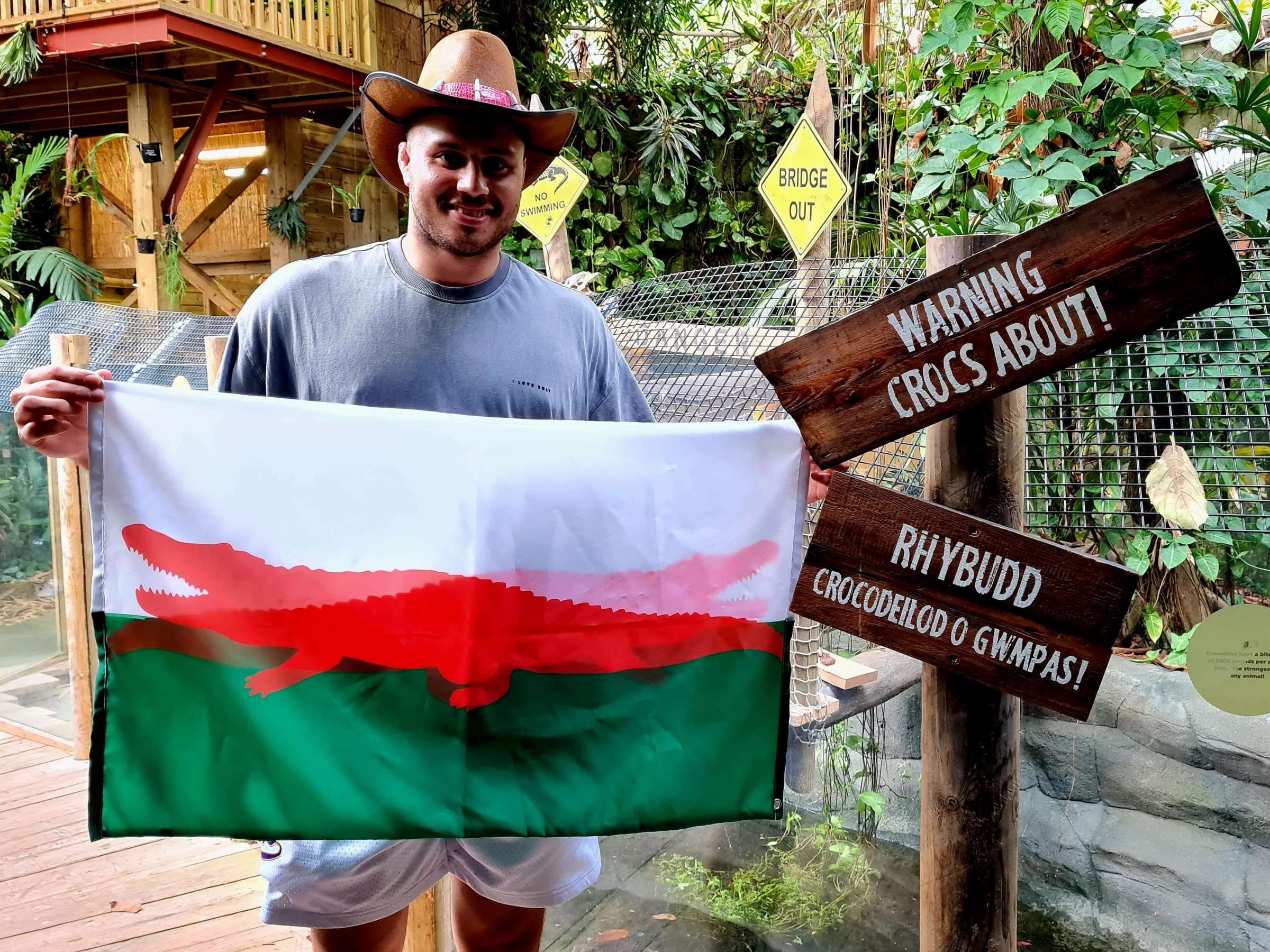 a man holding a Welsh flag with a red crocodile in place of a dragon