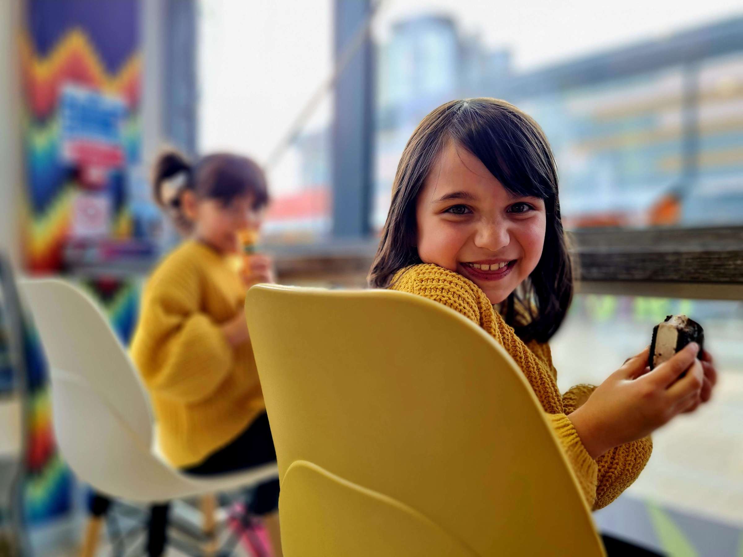a little girl holding an ice-cream and smilimg at the camera