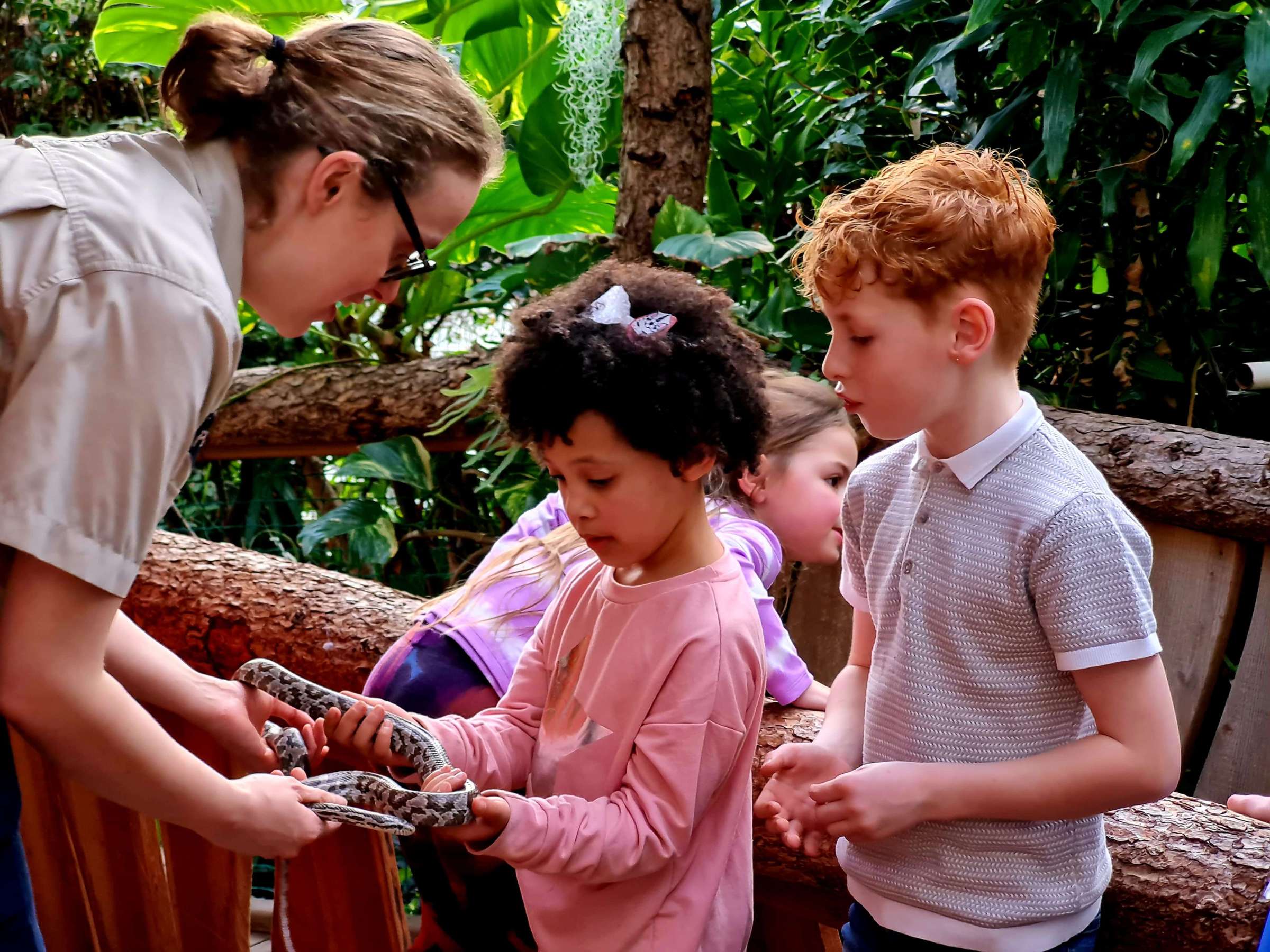 a young girl and zookeeper holding a snake