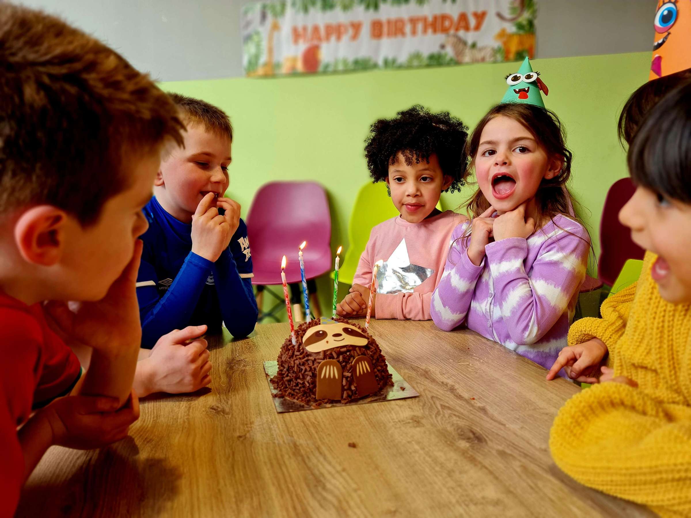 a group of children around a birthday cake
