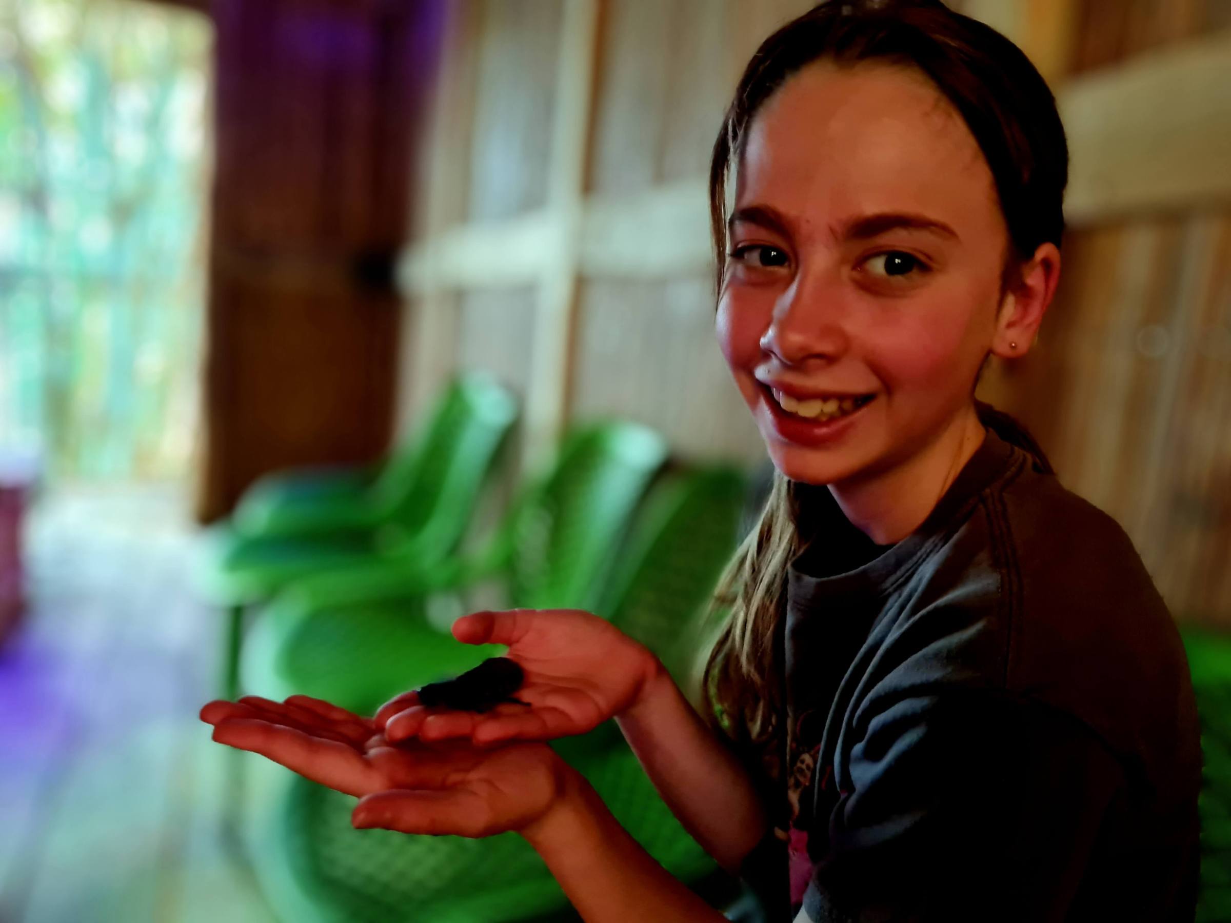 a smiling young girl holding a hissing cockroach