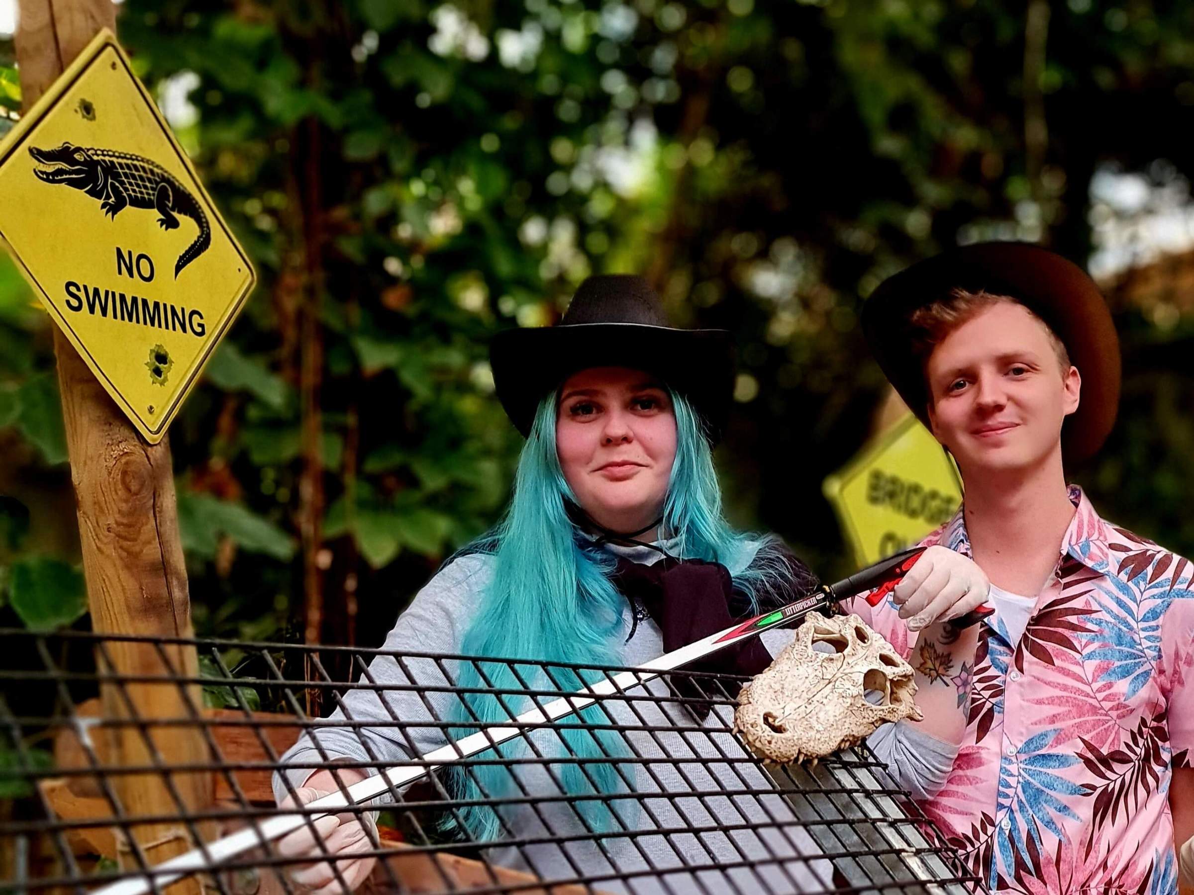 Two people standing behind a fence ready to feed the crocodiles