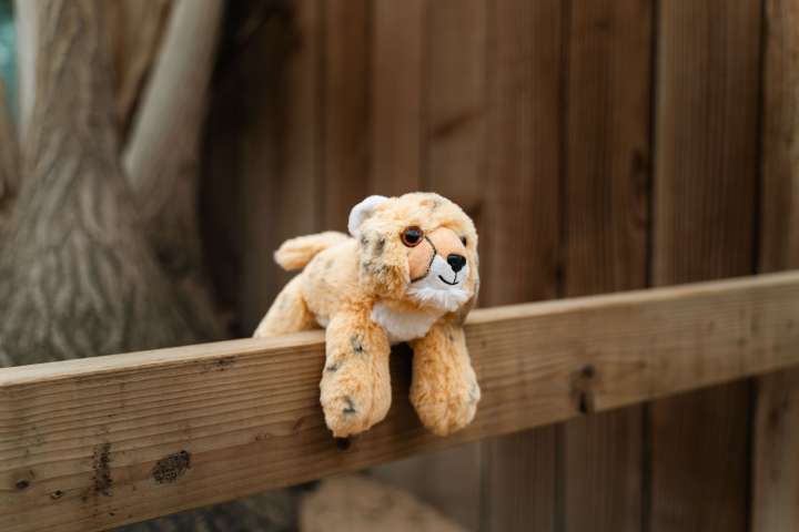 a leopard cat toy sitting on top of a wooden fence