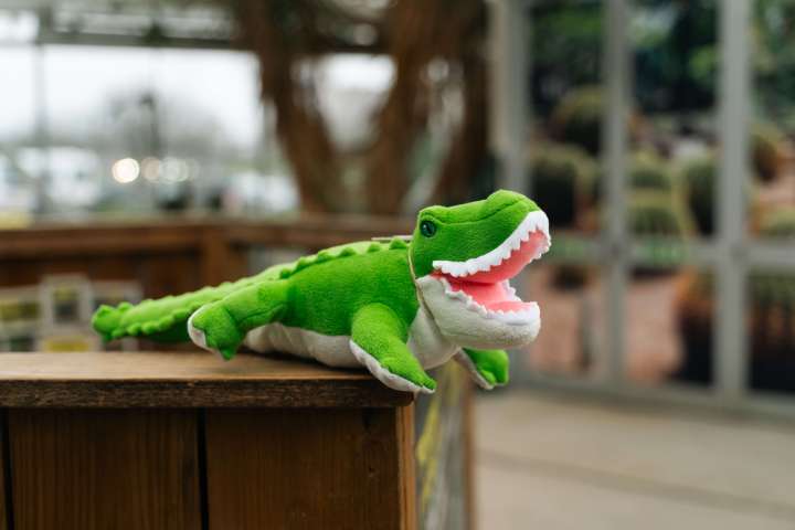 a crocodile toy sitting on top of a wooden shelf