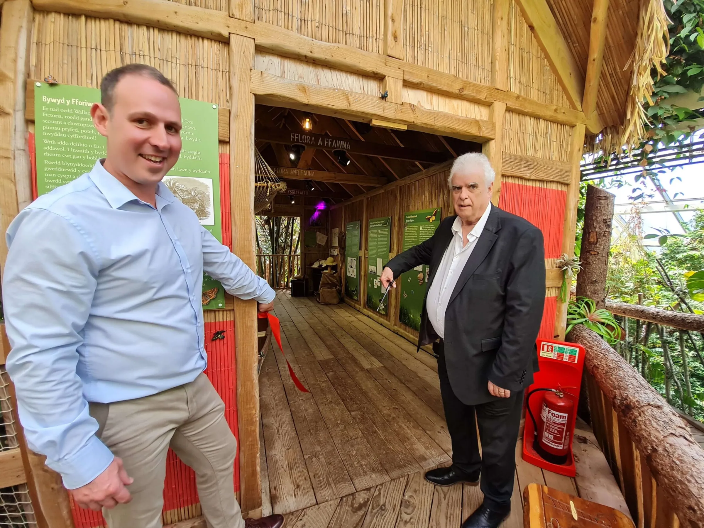 Two men standing either side of a treehouse entrance