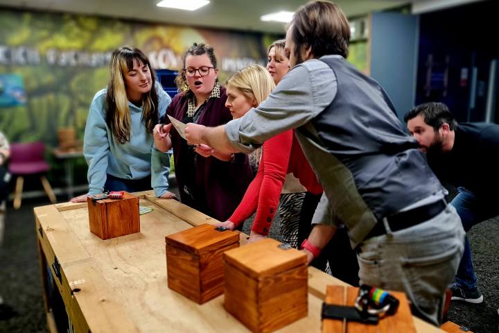 A group of people in front of several wooden boxes working together