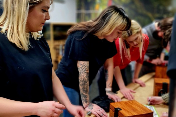 A group of women looking at wooden boxes
