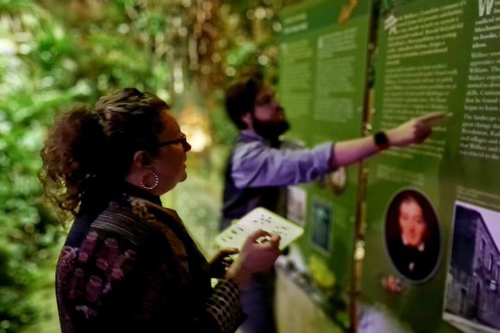a man and woman pointing and looking at a green board