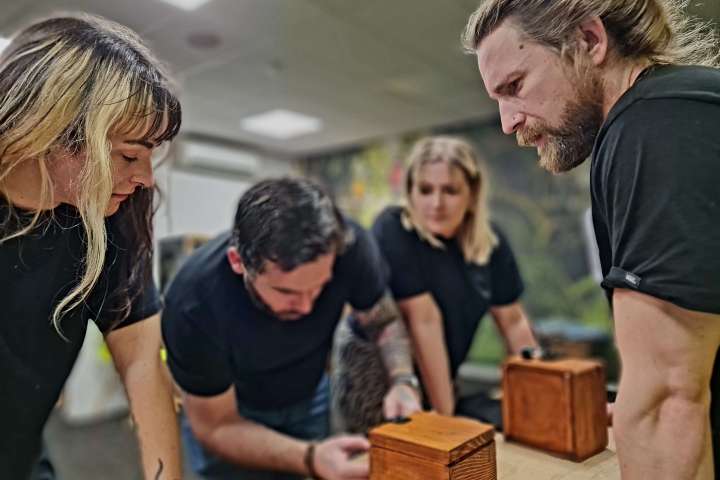a group of people trying to open a wooden box