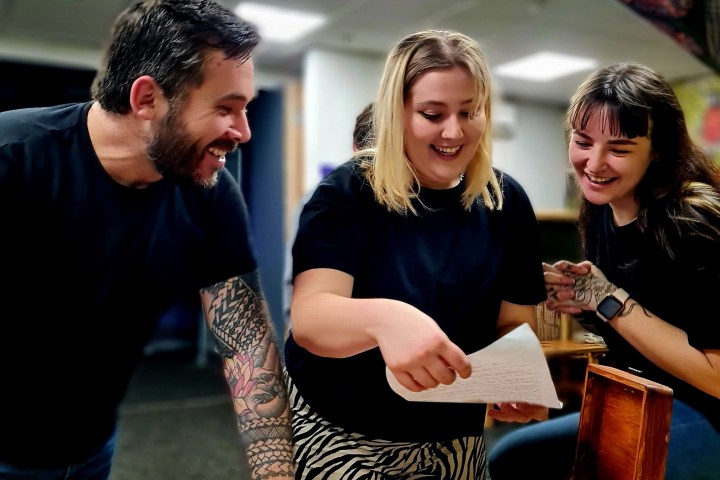 a group of people smiling and looking at a piece of paper