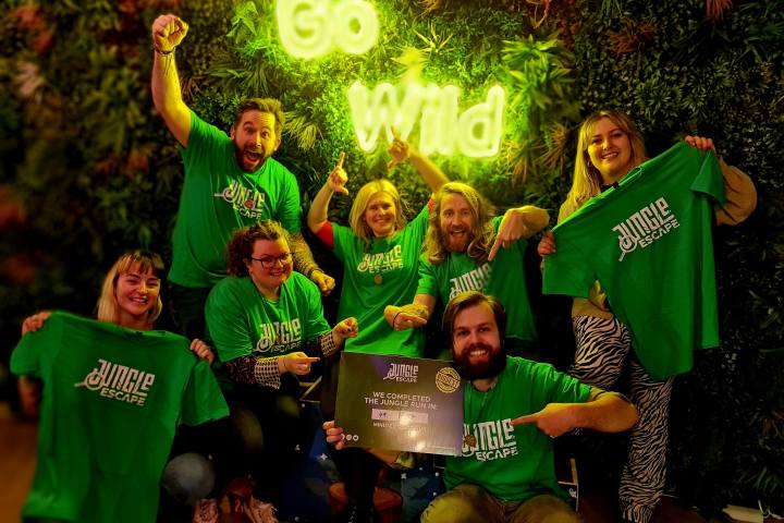 a group of people posing for the camera holding green Jungle Escape t-shirts
