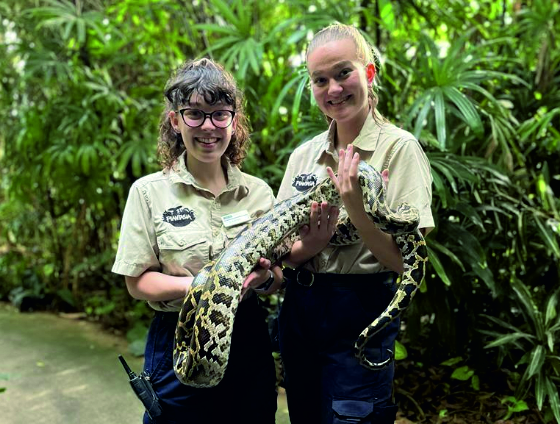 2 girl zookeepers holding a large python