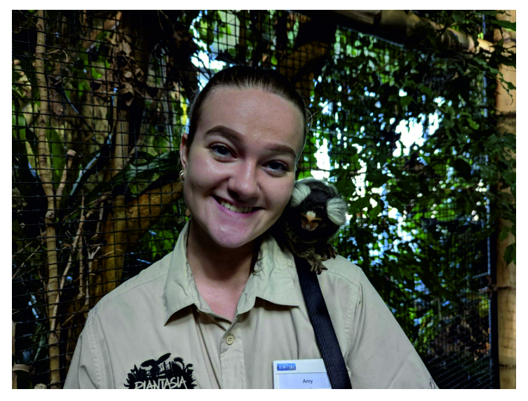 a girl posing for the camera with a monkey on her shoulder