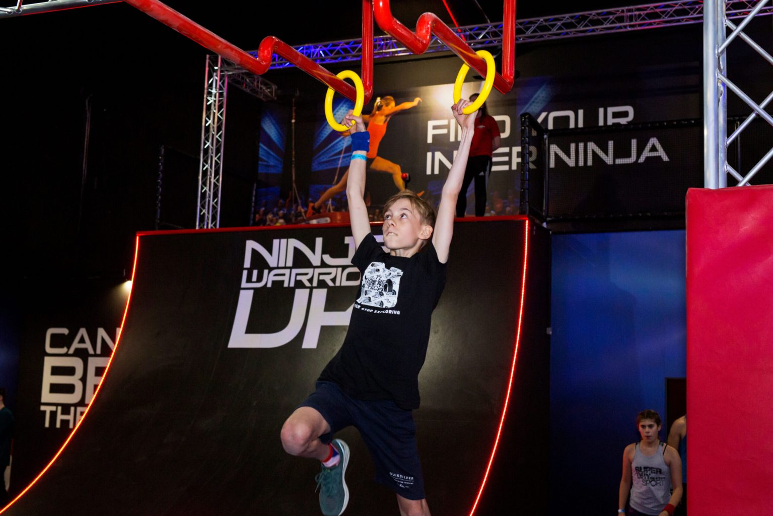a child hanging from hoops on an assault course