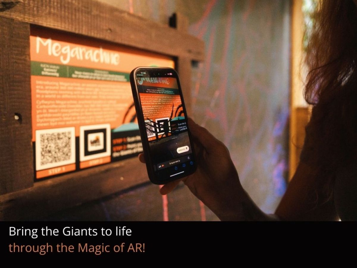 A person holding a mobile phone pointed at a sign with information about Megarachne