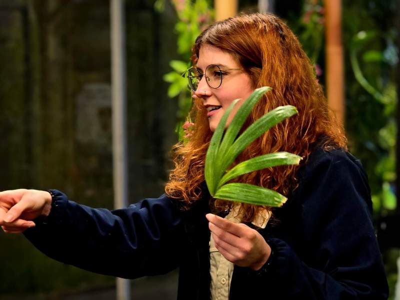 Education a female zookeeper holding a leaf and pointing at something