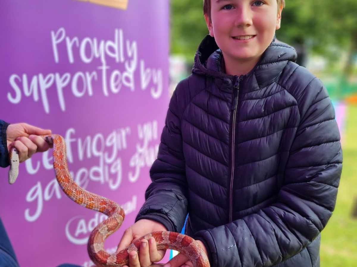 a young boy holding a snake, smiling for the camera