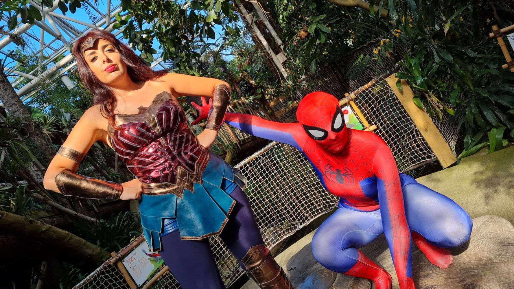 People in superhero costumes pose in a lush indoor garden.